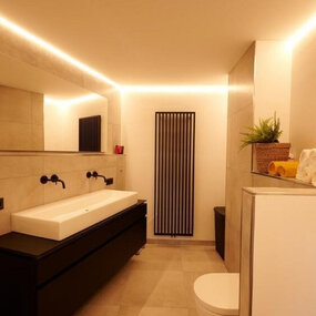 Modernes Badezimmer mit großem Spiegel, Doppelwaschbecken und indirekter LED-Beleuchtung.